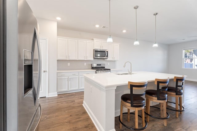 kitchen with stainless steel appliances, wood finished floors, a sink, and tasteful backsplash