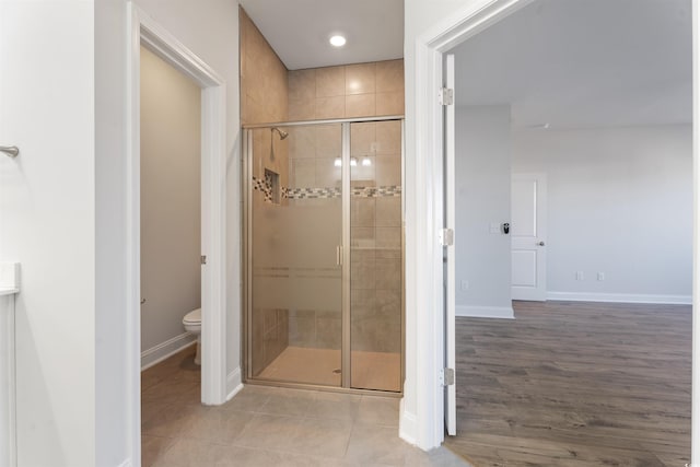 bathroom featuring tile patterned floors, a shower stall, toilet, and baseboards