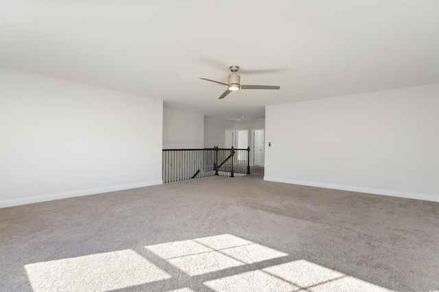 spare room with carpet floors, ceiling fan, and baseboards