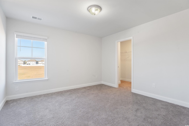 spare room featuring baseboards, visible vents, and carpet flooring