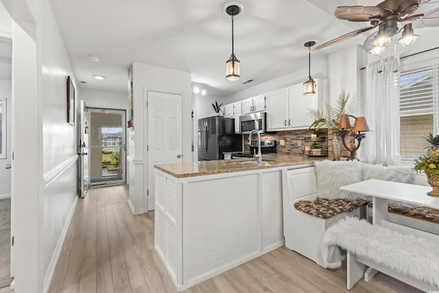 218 Landing Rd Unit G, North Myrtle Beach, SC 29582 - kitchen with a peninsula, light stone countertops, decorative backsplash, ceiling fan, and white cabinets