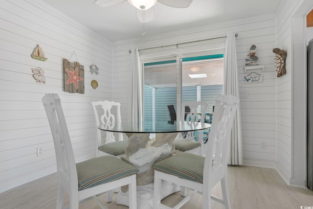 dining room featuring light wood-type flooring, baseboards, and a ceiling fan