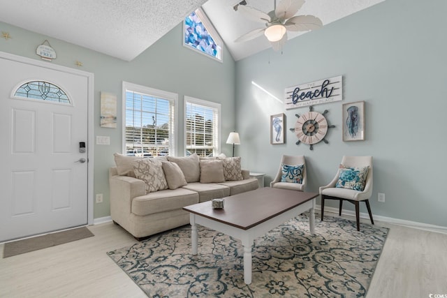 living area with lofted ceiling, light wood-style flooring, baseboards, and a textured ceiling