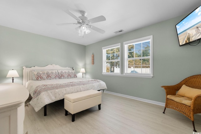 bedroom featuring light wood finished floors, a ceiling fan, visible vents, and baseboards