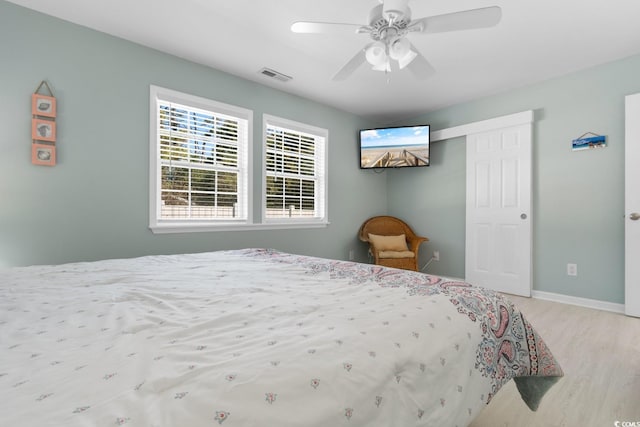 bedroom with ceiling fan, wood finished floors, visible vents, and baseboards