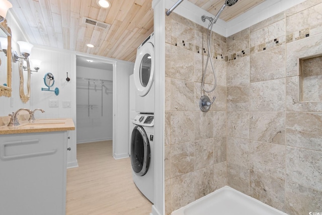 laundry area with wooden ceiling, light wood-style flooring, laundry area, a sink, and stacked washing maching and dryer