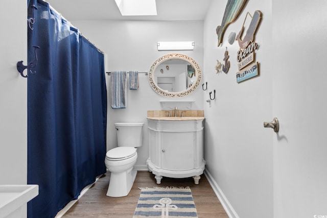 bathroom with a skylight, baseboards, toilet, and wood finished floors