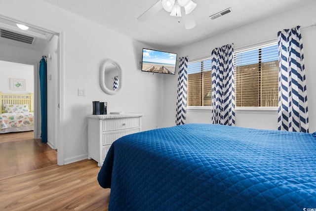 bedroom featuring a textured ceiling, wood finished floors, visible vents, and a ceiling fan