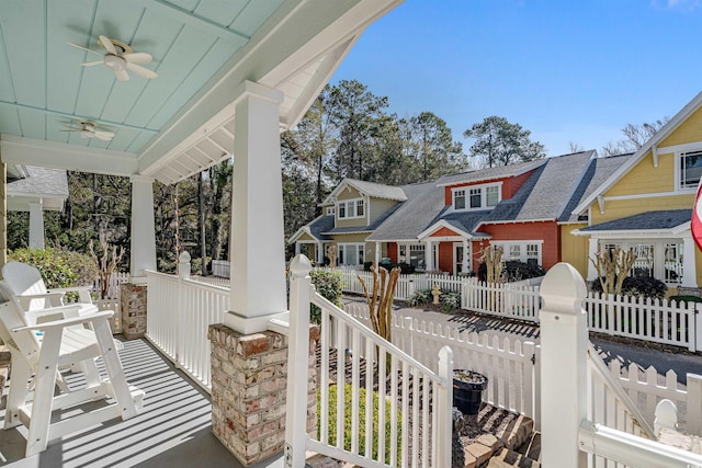 exterior space with a porch, a fenced front yard, a residential view, and a ceiling fan