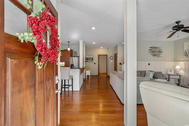 corridor with a wainscoted wall, recessed lighting, and light wood-style floors