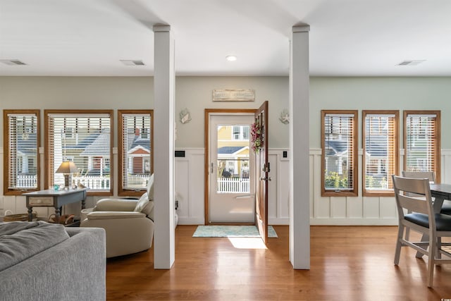 entrance foyer featuring light wood-style floors, visible vents, a decorative wall, and a wainscoted wall