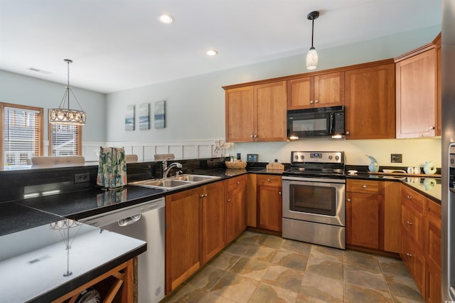 kitchen with appliances with stainless steel finishes, dark countertops, brown cabinetry, and a sink