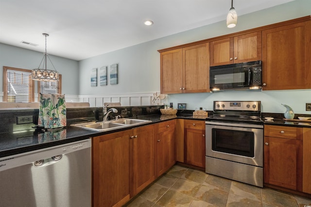 kitchen with stainless steel appliances, brown cabinets, a sink, and hanging light fixtures