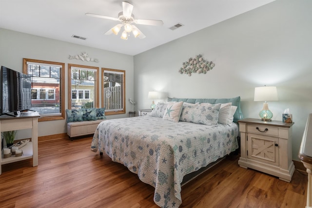 bedroom featuring ceiling fan, wood finished floors, visible vents, and baseboards