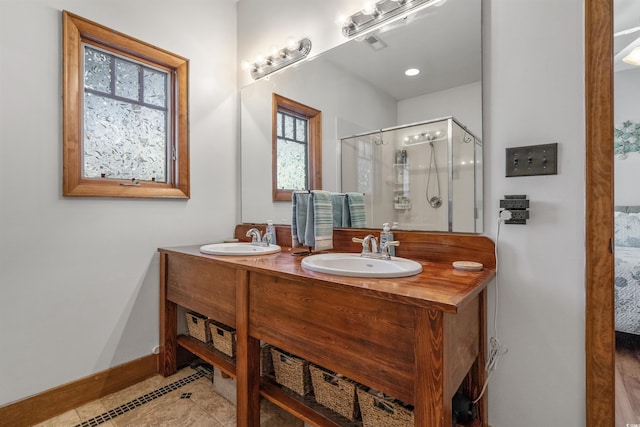 full bath with tile patterned floors, a stall shower, a sink, and baseboards