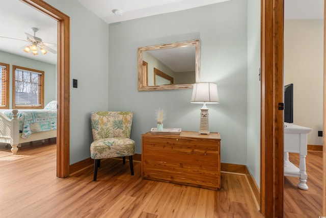 sitting room featuring a ceiling fan, light wood-style flooring, and baseboards