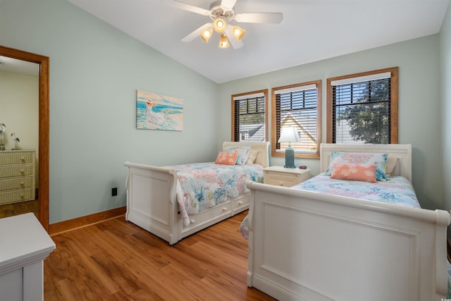 bedroom featuring light wood finished floors, baseboards, vaulted ceiling, and a ceiling fan