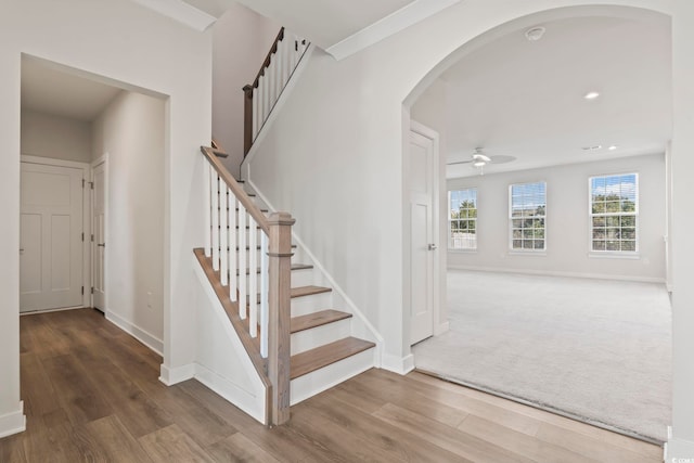 staircase featuring baseboards, arched walkways, ceiling fan, wood finished floors, and recessed lighting