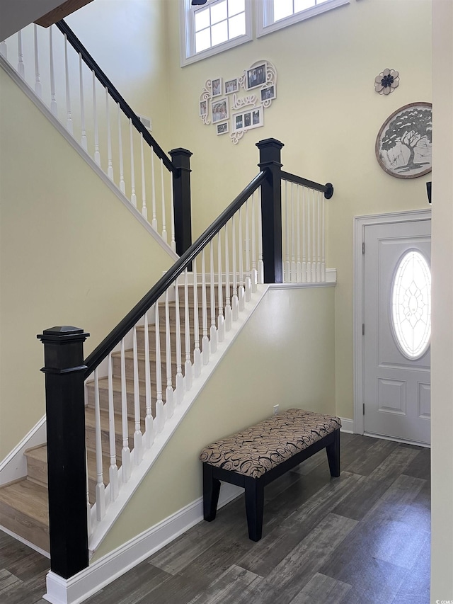 entrance foyer with stairs, wood finished floors, baseboards, and a towering ceiling