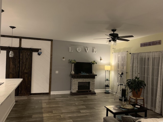 living room with dark wood-style floors, baseboards, visible vents, ceiling fan, and a stone fireplace