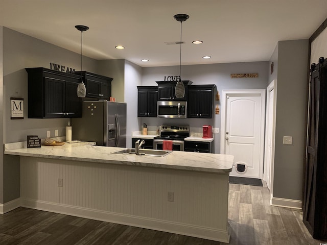 kitchen with dark cabinetry, visible vents, a peninsula, a sink, and appliances with stainless steel finishes