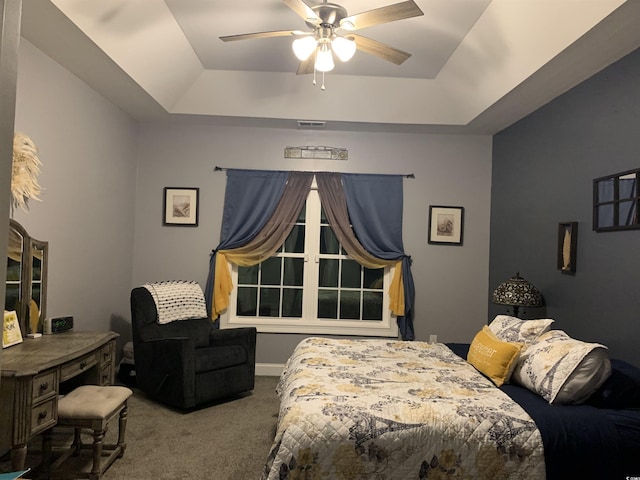 carpeted bedroom featuring a raised ceiling, visible vents, and ceiling fan