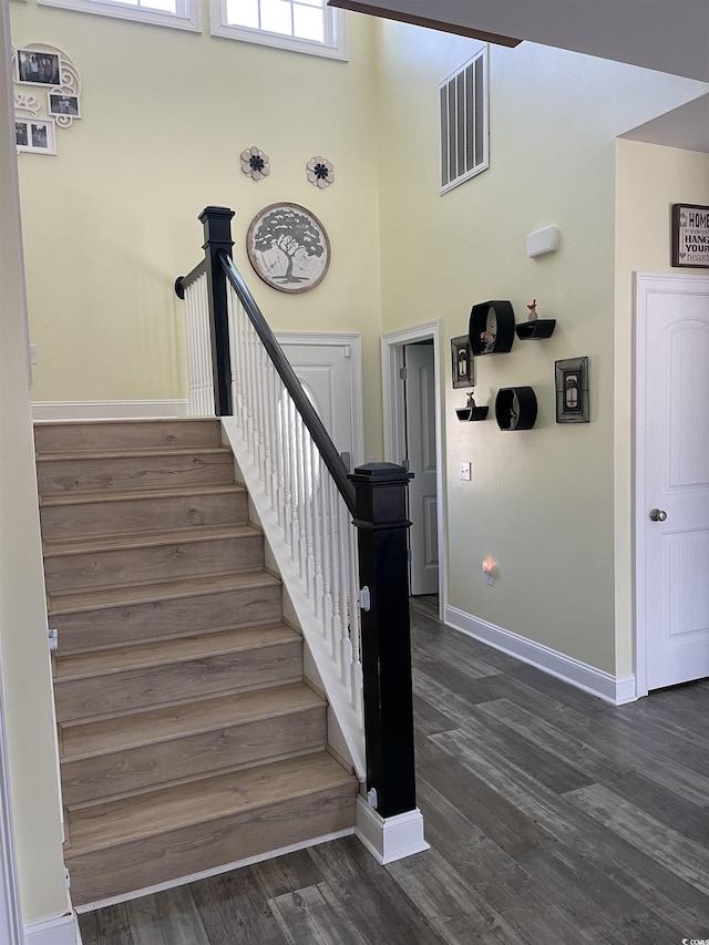 staircase featuring wood finished floors, visible vents, and baseboards