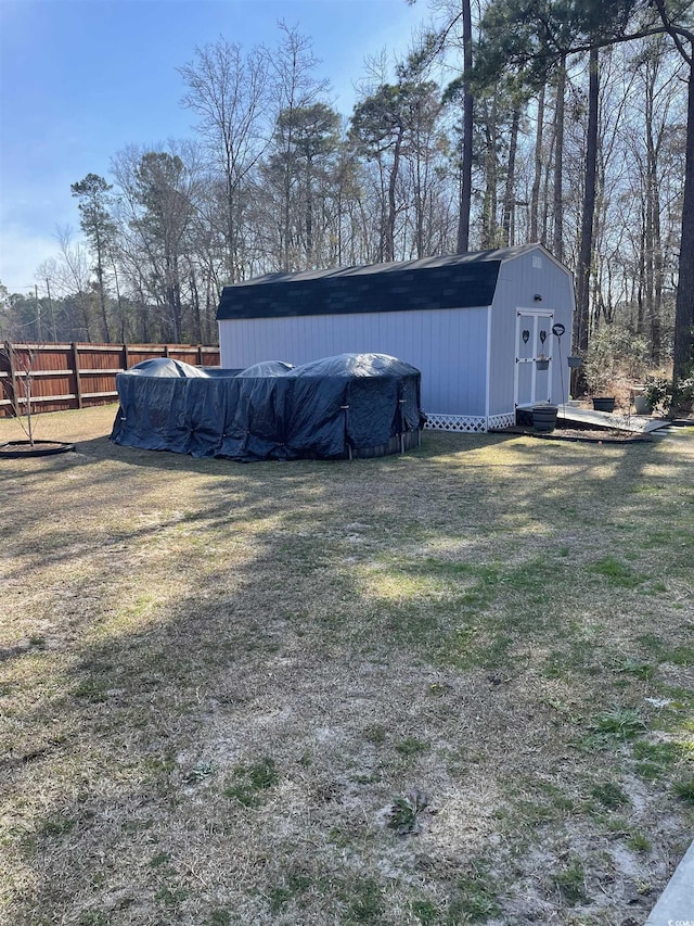 view of yard featuring a pool, a shed, an outdoor structure, and fence