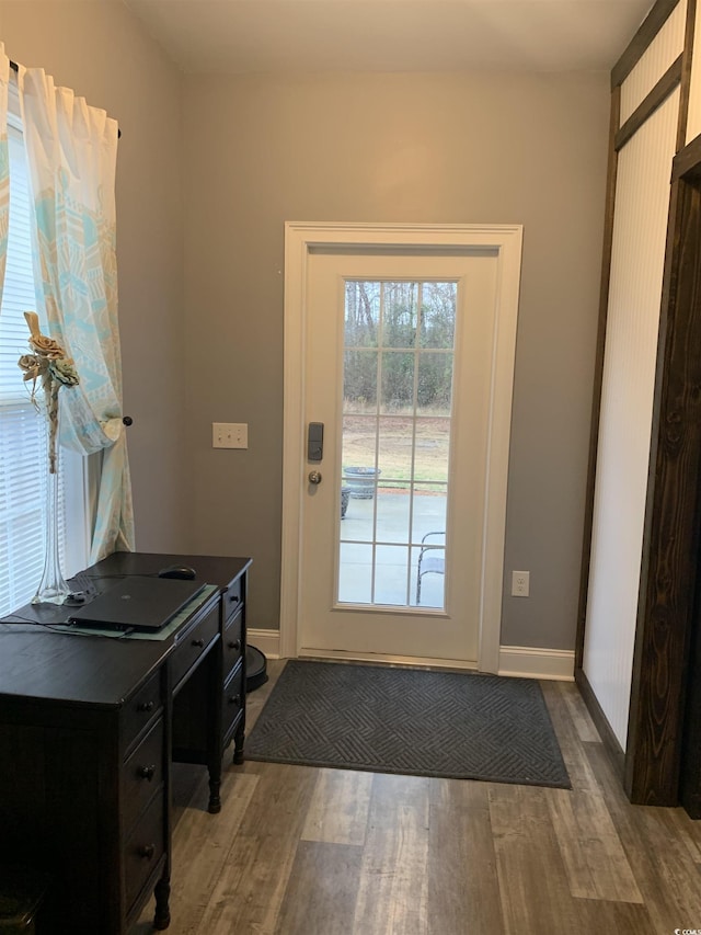 doorway featuring baseboards and wood finished floors