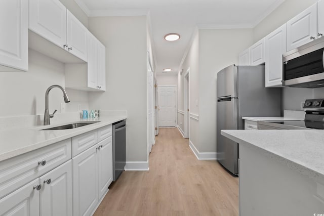 kitchen with stainless steel appliances, white cabinetry, a sink, and ornamental molding