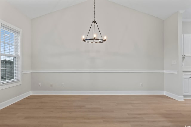 unfurnished dining area featuring lofted ceiling, light wood finished floors, baseboards, and a notable chandelier