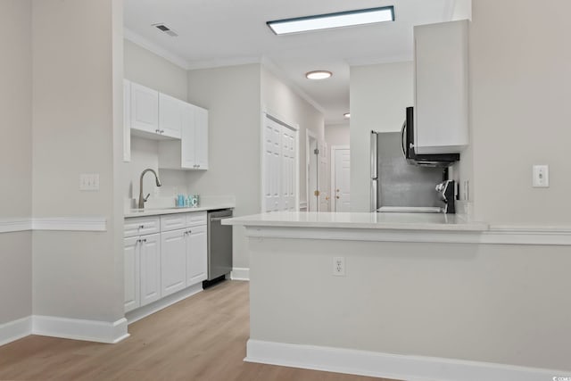 kitchen featuring stainless steel appliances, light countertops, white cabinets, and a sink