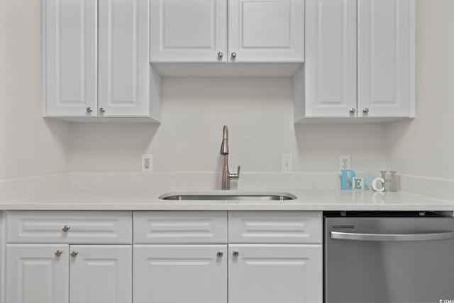 kitchen with a sink, white cabinets, stainless steel dishwasher, and light countertops