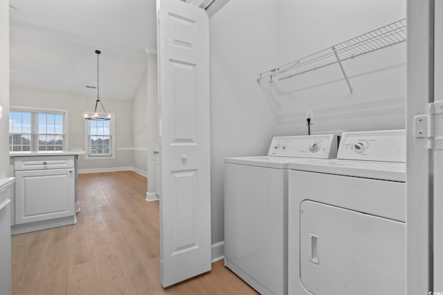 clothes washing area featuring laundry area, baseboards, light wood-style flooring, and washing machine and clothes dryer