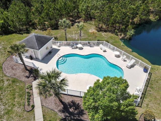 community pool featuring an outbuilding, a patio area, a fenced backyard, and a water view