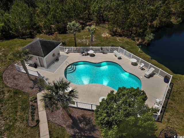 pool featuring a water view, a patio area, a fenced backyard, and an outbuilding