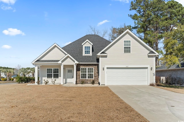 view of front of home with a shingled roof, concrete driveway, a front yard, a garage, and stone siding