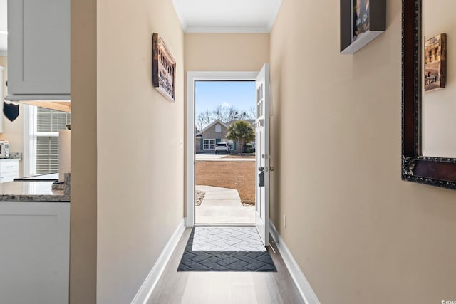 hallway with baseboards, crown molding, and wood finished floors