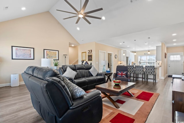 living area featuring light wood finished floors, visible vents, high vaulted ceiling, baseboards, and stairs