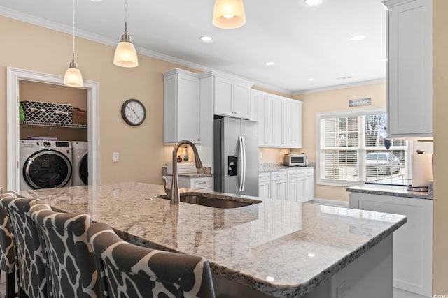 kitchen with crown molding, washing machine and dryer, a sink, and stainless steel refrigerator with ice dispenser