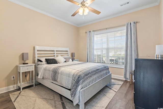 bedroom with visible vents, crown molding, baseboards, and wood finished floors