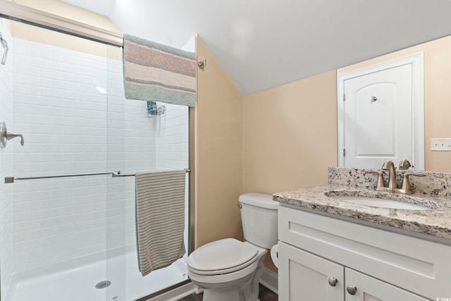 bathroom featuring toilet, a stall shower, vaulted ceiling, and vanity