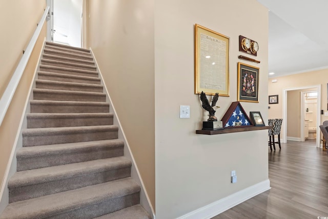 stairs with crown molding, baseboards, and wood finished floors