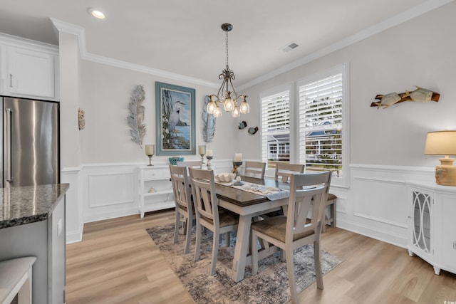 dining area with a notable chandelier, visible vents, light wood finished floors, and ornamental molding