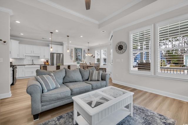 living area with baseboards, light wood-style floors, and ornamental molding