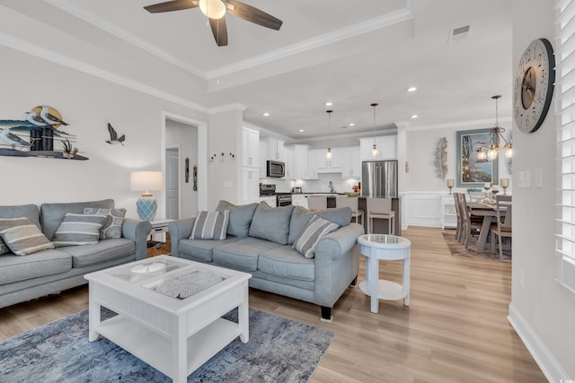 living room with visible vents, ceiling fan with notable chandelier, recessed lighting, crown molding, and light wood finished floors