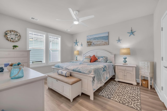 bedroom featuring a ceiling fan, light wood-style floors, visible vents, and baseboards