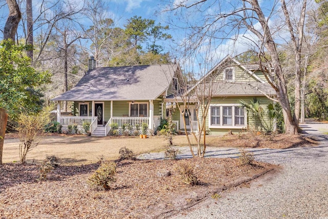 view of front of home featuring covered porch, driveway, and a chimney