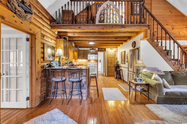 kitchen featuring white microwave, light wood-style flooring, freestanding refrigerator, a peninsula, and high vaulted ceiling