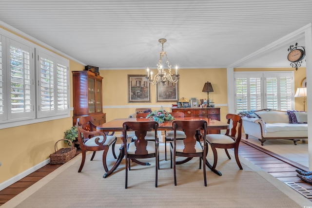 dining area featuring ornamental molding, wood finished floors, and a notable chandelier